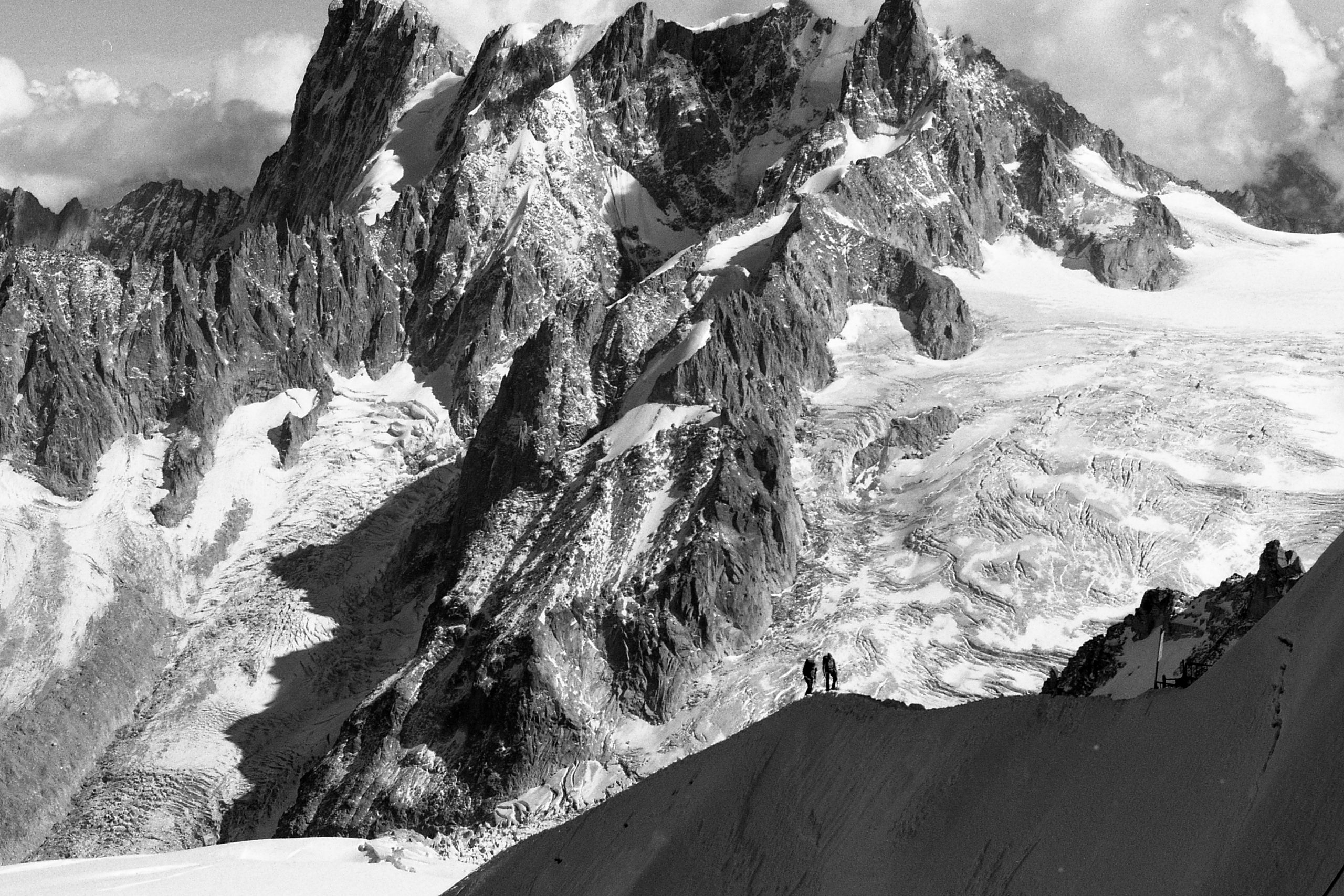 Deux alpinistes gravissant le Mont Blanc enneigé, illustrant la relation de confiance avec les partenaires financiers d'Aravis Partenaires.
